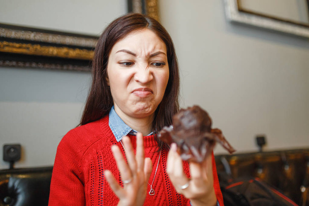 Uma mulher com um rosto engraçado não gosta de um queque de bolo estragado em um café
 - Foto, Imagem