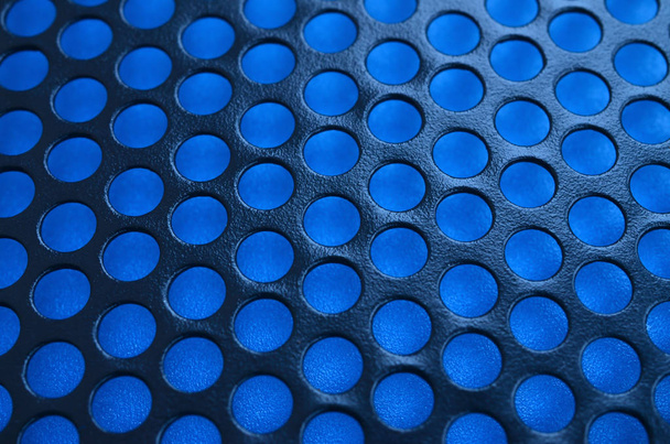 Černý kovový počítače případ panel síťoviny s otvory na modrém pozadí. Abstraktní Zavřít obrázek - Fotografie, Obrázek