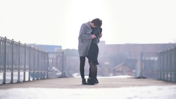 Νεαρός Καυκάσιος άνδρας και γυναίκα που περπατά αγκάλιασε σε μια θυελλώδη ημέρα - Πλάνα, βίντεο