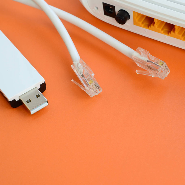 Internet router, portable USB wi-fi adapter and internet cable plugs lie on a bright orange background. Items required for internet connection - Photo, Image