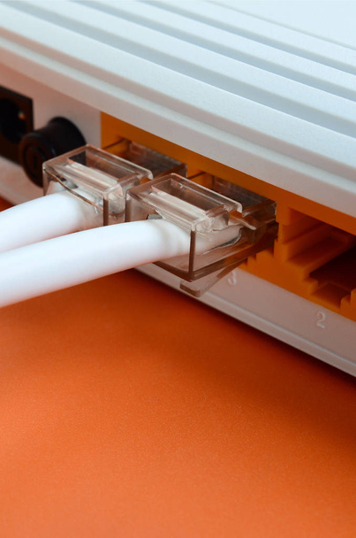 インター ネット ケーブルのプラグは、明るいオレンジ色の背景上にあるインターネットのルーターに接続されます。インターネット接続に必要な項目 - 写真・画像