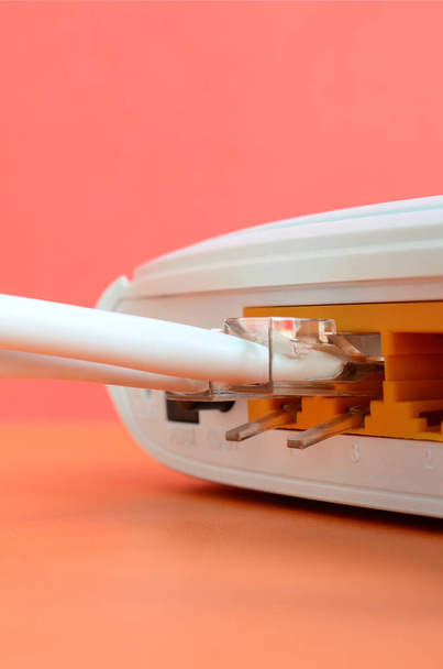 Los enchufes de cable de Internet están conectados al enrutador de Internet, que se encuentra sobre un fondo naranja brillante. Elementos necesarios para la conexión a Internet
 - Foto, imagen