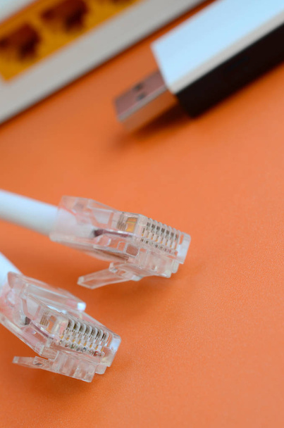 Интернет-роутер, портативный адаптер wi-fi и вилки интернет-кабеля лежат на ярко-оранжевом фоне. Элементы, необходимые для подключения к Интернету
 - Фото, изображение