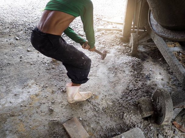 Trabajador rompiendo con martillo de trineo en el suelo
. - Foto, imagen