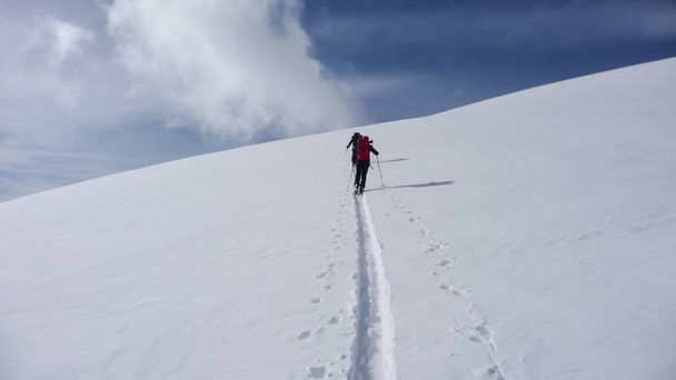 two backcountry skiers on a tour in the Austrian Alps and putting in new tracks on their way to the summit - Foto, afbeelding