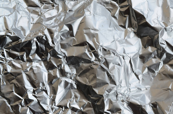 dünne runzelige Blatt aus zerkleinertem Zinn Aluminium-Silberfolie Hintergrund mit glänzenden zerknitterten Oberfläche für die Textur - Foto, Bild