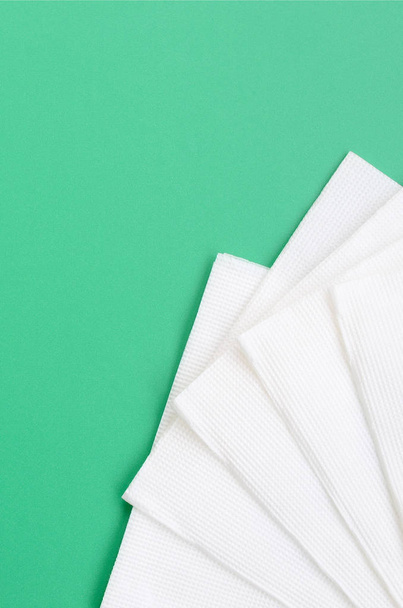 Several white paper napkins lie on a plastic green background - Photo, Image