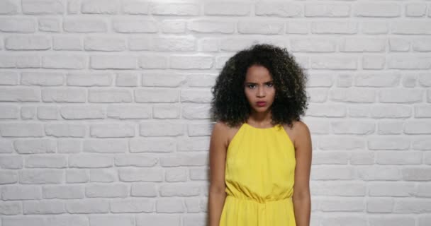 Mimika młody czarny kobieta na ceglany mur - Materiał filmowy, wideo