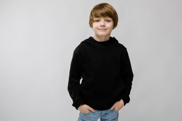 mignon caucasien garçon dans noir tenue montrant différentes expressions sur blanc mur dans studio
. - Photo, image