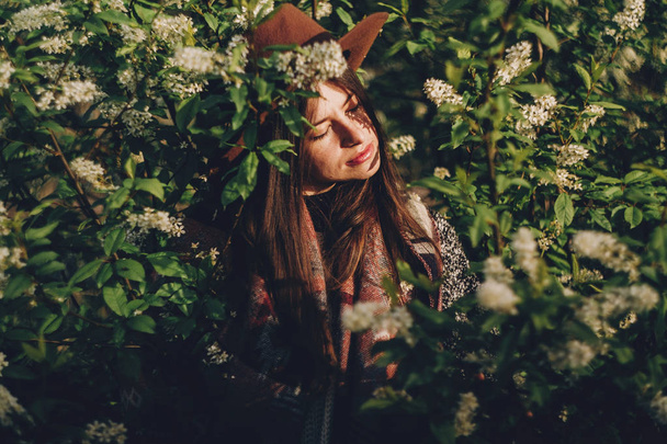akşam güneş ışığı altında Gölgeler arasında çiçekli yeşil poz şapkalı güzel hippi kız bırakır. şık kadın Gezgin bahar bahçe sakin portre. metin için yer. Atmosferik an - Fotoğraf, Görsel