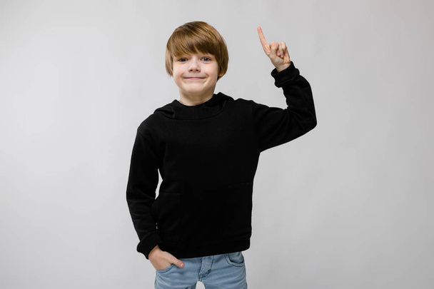 Aranyos kaukázusi fiú fekete ruhában, mutatja a különböző kifejezések fehér falon a stúdió. - Fotó, kép