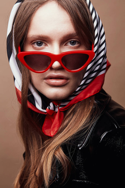 Retro style portrait of amazing young woman in red cat eye sunglasses and retro headscarf with black, white and red stripes  - Foto, imagen