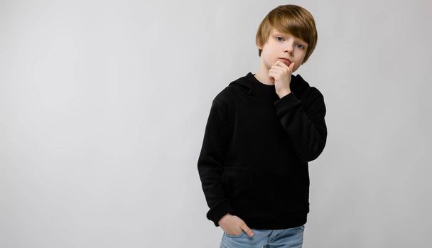 Милый кавказский мальчик в черном, с разными выражениями лица на белой стене в студии.
. - Фото, изображение