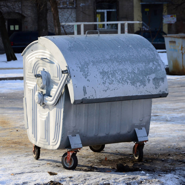 Ein silberner Müllcontainer steht in der Nähe von Wohnhäusern in  - Foto, Bild