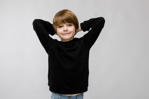Χαριτωμένο αγόρι Καυκάσιος σε μαύρο ρούχο που παρουσιάζουν διαφορετικές εκφράσεις στον λευκό τοίχο στο studio. - Φωτογραφία, εικόνα
