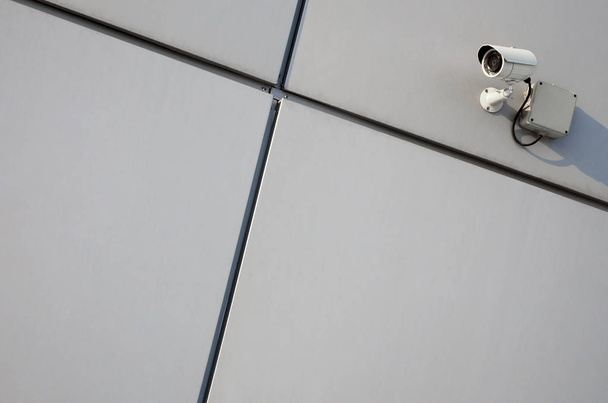 White surveillance camera built into the metal wall of the office building - Photo, Image