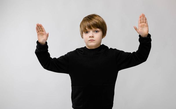 bonito caucasiano menino no preto roupa mostrando diferentes expressões no branco parede no estúdio
. - Foto, Imagem