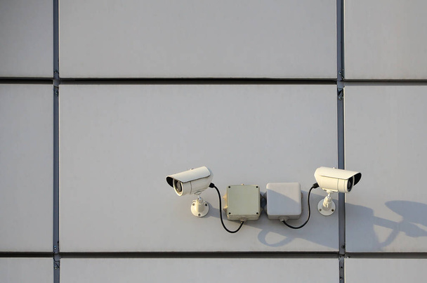 Cámara de vigilancia blanca incorporada en la pared metálica del edificio de oficinas
 - Foto, imagen