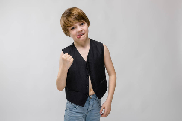 Cute caucasian boy in black waistcoat showing different expressions on white wall in studio. - Photo, Image