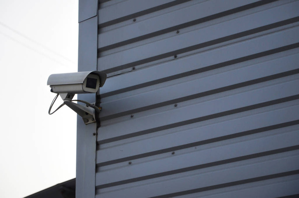 White surveillance camera built into the metal wall of the office building - Foto, Imagen