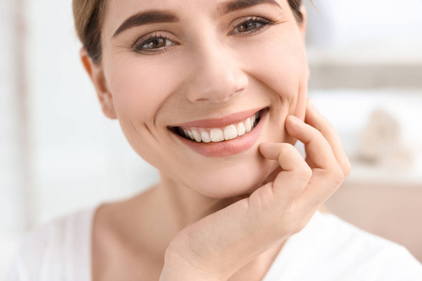 Young woman with beautiful smile indoors. Teeth whitening - 写真・画像