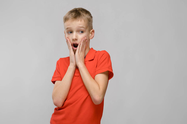 Cute blond caucasian preteen boy in bright t-shirt showing different expressions on white wall in studio. - Photo, image