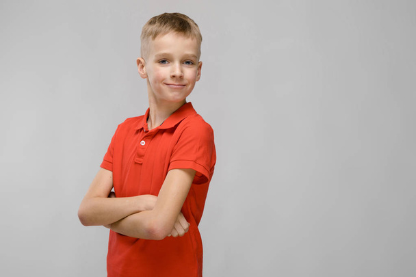 Cute blond caucasian preteen boy in bright t-shirt showing different expressions on white wall in studio. - Photo, Image