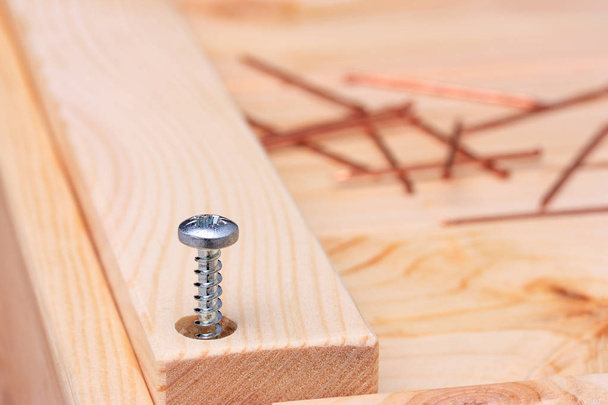 The screw is half twisted into a wooden board. - Foto, immagini
