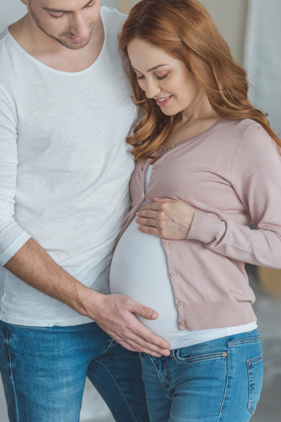 cropped shot of happy man touching belly of pregnant wife - Фото, изображение