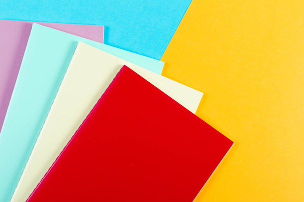 Colorful notebooks on blue and yellow background - Foto, Bild