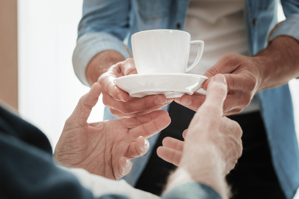 A cup of warm tea being in mans hands. - Фото, изображение