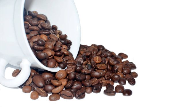 Κόκκους καφέ που πέφτουν από ένα φλιτζάνι καφέ σε λευκό φόντο. Κοντινό πλάνο - Φωτογραφία, εικόνα