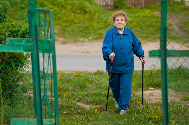 Active old woman (85 years old) nordic walking outdoors. - Photo, Image