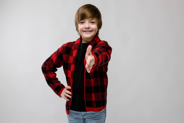 Szép, preteen kaukázusi fiú alkalmi ruhát mutatja a különböző kifejezések fehér falon a stúdióban. Segítő kéz. - Fotó, kép