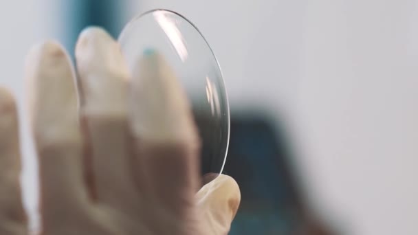 Ingenieur in rubberen handschoenen schoonmaken geproduceerd vergrootglas lens tegen licht - Video
