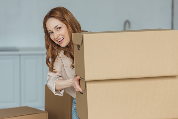 portrait of cheerful woman with cardboard boxes at new home, relocation concept - Foto, afbeelding