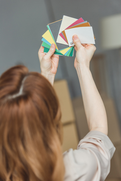back view of woman choosing color for room at new home, relocation concept - Photo, Image