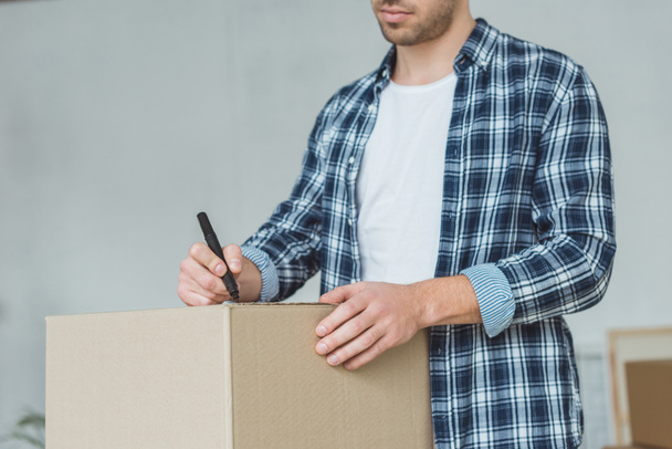cropped shot of man signing cardboard box for moving home, relocation concept - Foto, afbeelding
