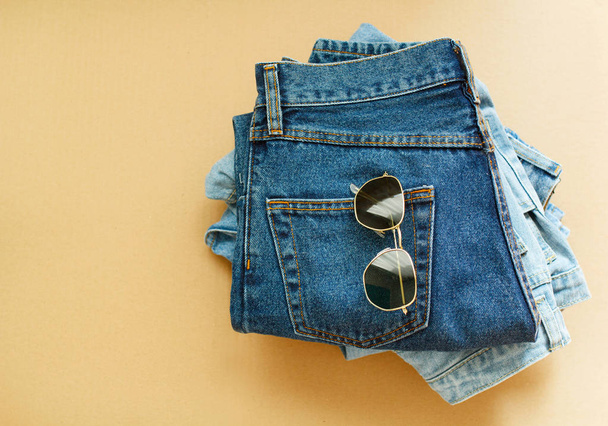 Picture of jeans with glasses on craft wooden background - 写真・画像