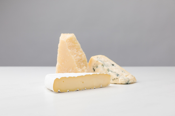 Close up view of brie, cheddar and blue cheese on gray  - 写真・画像