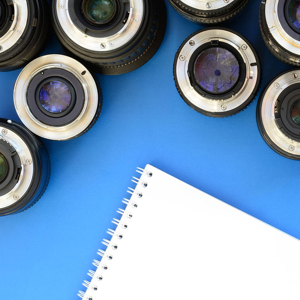 Várias lentes fotográficas e caderno branco jazem em um b brilhante
 - Foto, Imagem