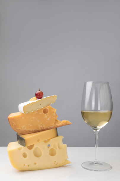 Beyaz Şarap kadehi ve üzüm görünümünü peynir gri farklı türde yığında kapatın - Fotoğraf, Görsel