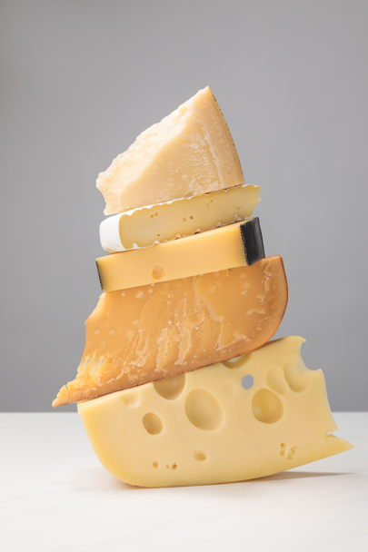 Close-up van stapel van verschillende soorten kaas op grijs - Foto, afbeelding