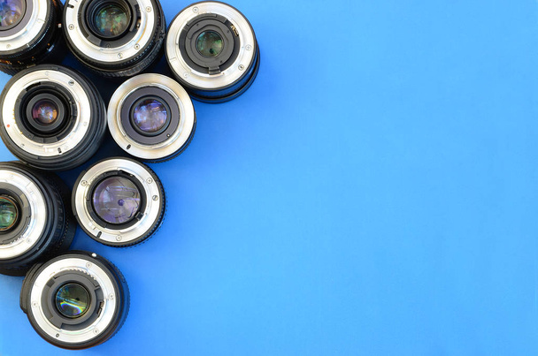 Várias lentes fotográficas repousam sobre um fundo azul brilhante. Espaço para texto
 - Foto, Imagem