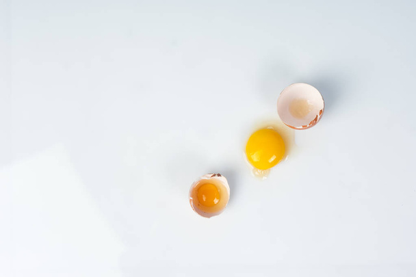 Yolk of broken egg in eggshell decorated with pink sisal nest on - Foto, afbeelding