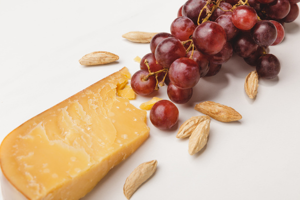 Closeup shot of parmesan cheese, almond and grapes on white - Fotó, kép