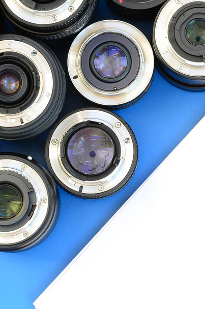 Varios lentes fotográficos y cuaderno blanco se encuentran sobre un fondo azul brillante. Espacio para texto
 - Foto, imagen