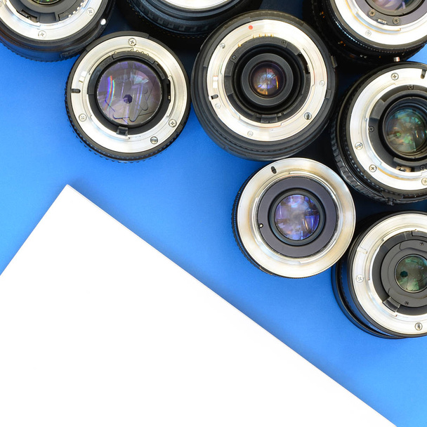 Varios lentes fotográficos y cuaderno blanco se encuentran sobre un fondo azul brillante. Espacio para texto
 - Foto, imagen