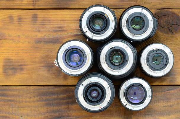 Várias lentes fotográficas repousam sobre um fundo de madeira marrom. Sp
 - Foto, Imagem