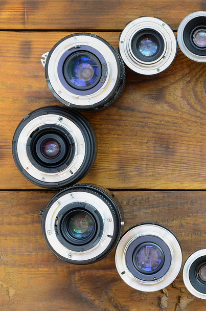 Varias lentes fotográficas se encuentran sobre un fondo de madera marrón. Espacio para texto
 - Foto, imagen